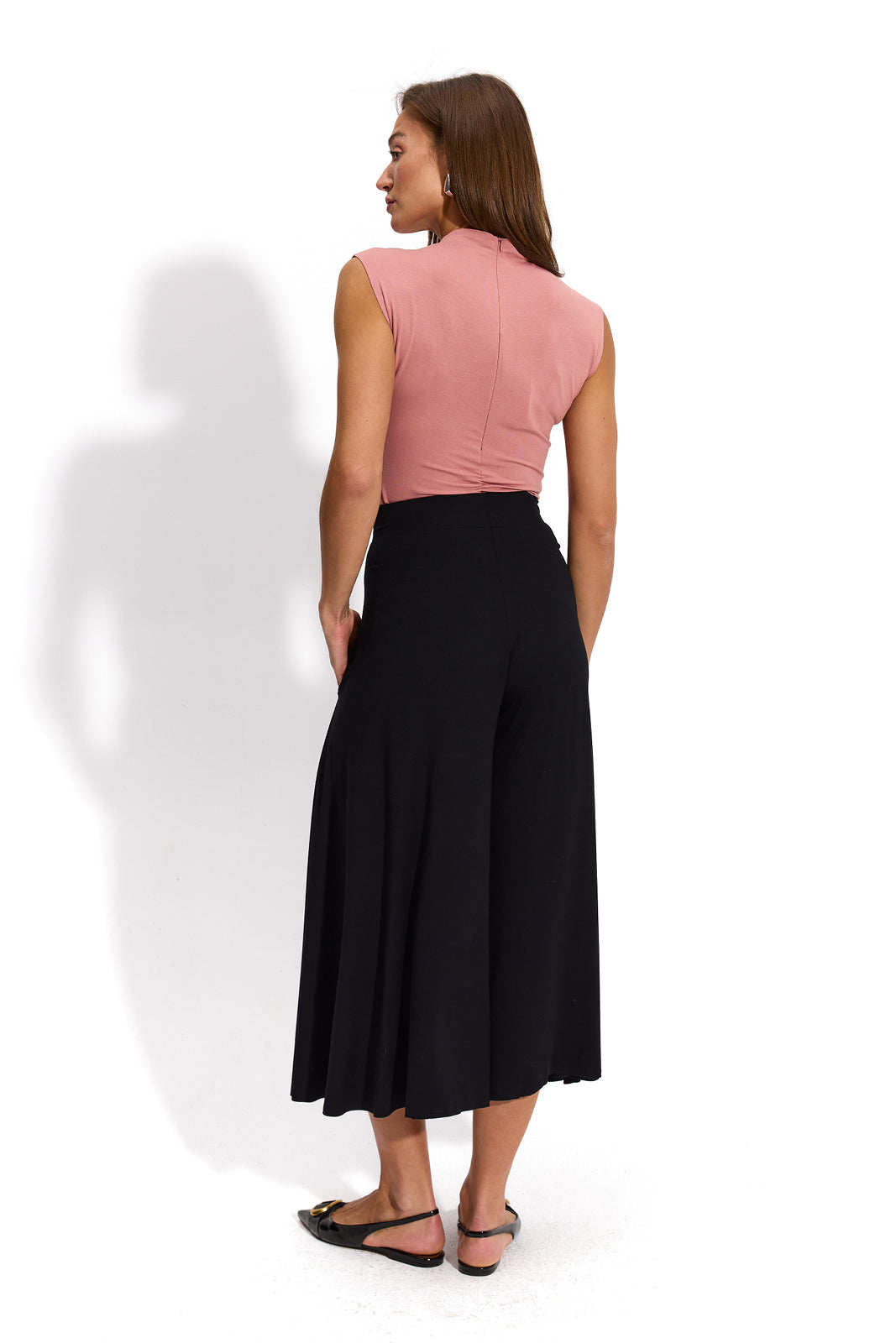 Różowa bezrękawnikowa bluzka i czarne spodnie typu culottes – elegancka stylizacja damska z precyzyjnym krojem