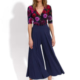 Kobieta w kwiecistej bluzce i granatowych spodniach culottes, stylowa moda damska z precyzyjnym krojem