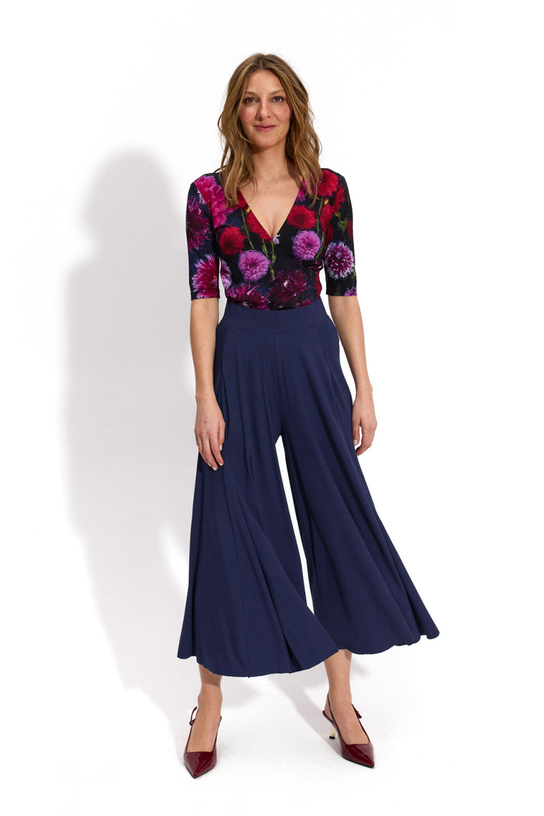 Kobieta w kwiecistej bluzce i granatowych spodniach culottes, stylowa moda damska z precyzyjnym krojem
