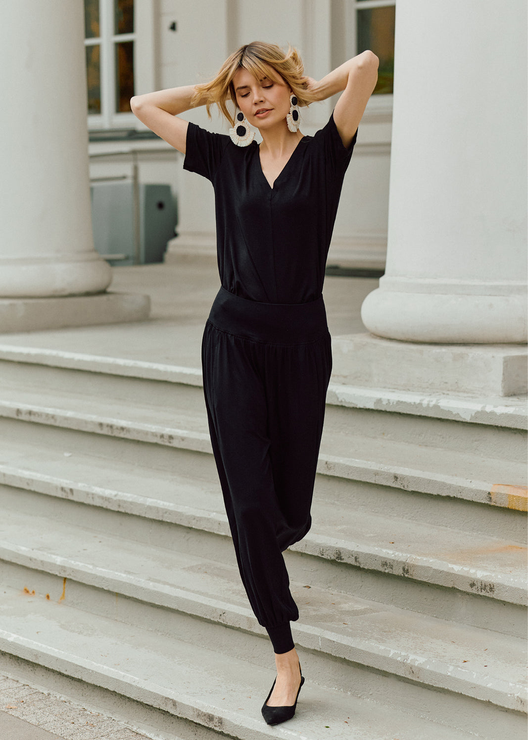 Czarny jumpsuit z dekoltem w kształcie litery V i elastyczną talią, idealny na co dzień, z eleganckimi kolczykami