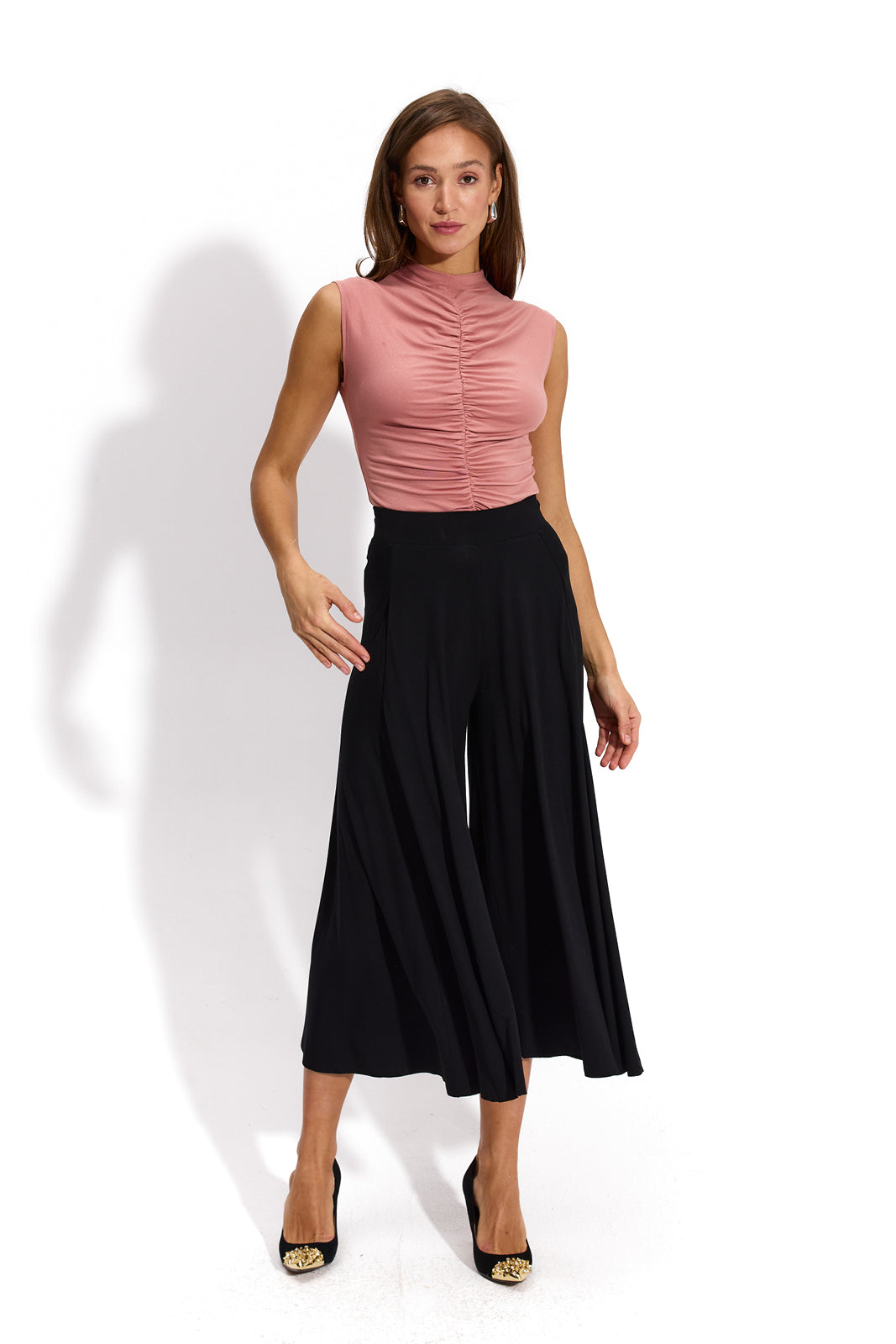 Różowa bluzka z marszczonymi detalemi i czarne spodnie typu culottes – elegancka stylizacja na co dzień