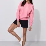 Różowy sweter damska stylizacja z czarnymi szortami i białymi butami, wygodna moda polska