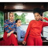 Trzy kobiety w stylowych, kolorowych ubraniach siedzą w tramwaju – moda polska, wygodna i elegancka