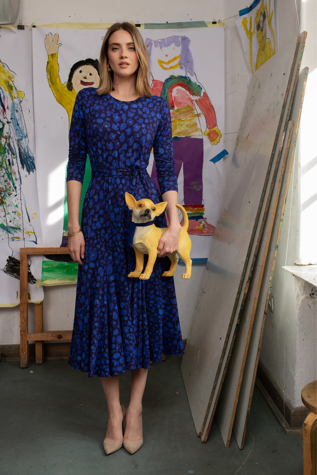Kobieta w niebieskiej sukience w wzory z małym psem w artystycznym studio, moda polska, self-care fashion