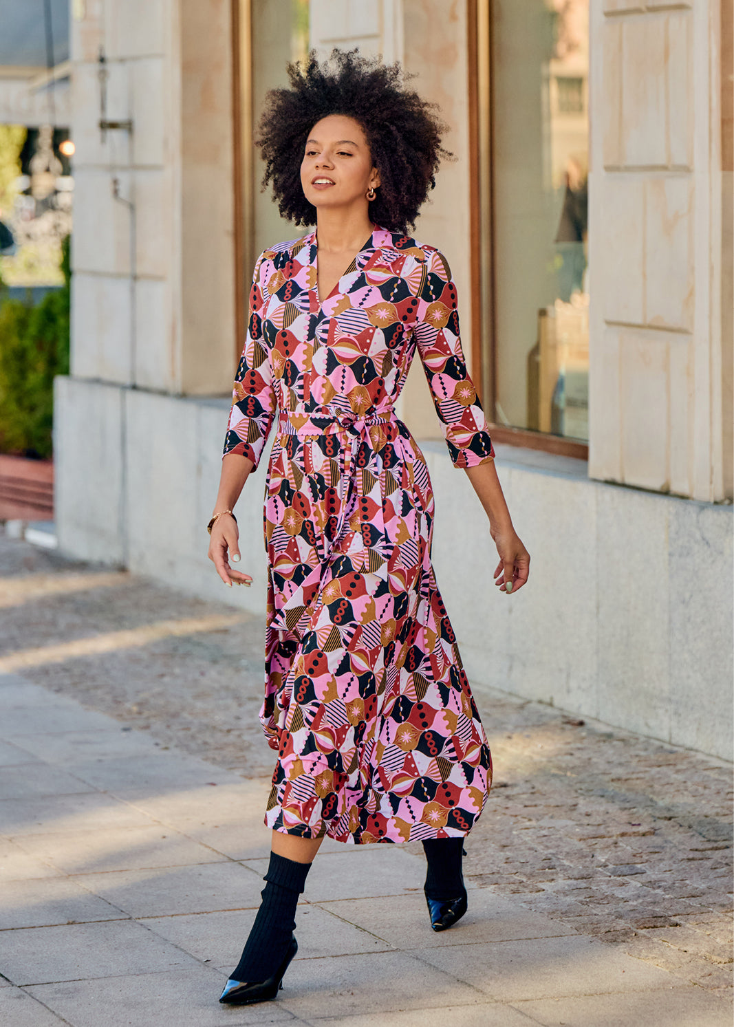 Kobieta w kolorowej, geometrycznej sukience midi z pasem, idealna na codzienne stylizacje i self-care fashion