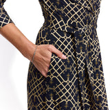 Elegancka sukienka w geometryczny wzór złoty na ciemnym tle, z kieszenią i wiązaniem w pasie