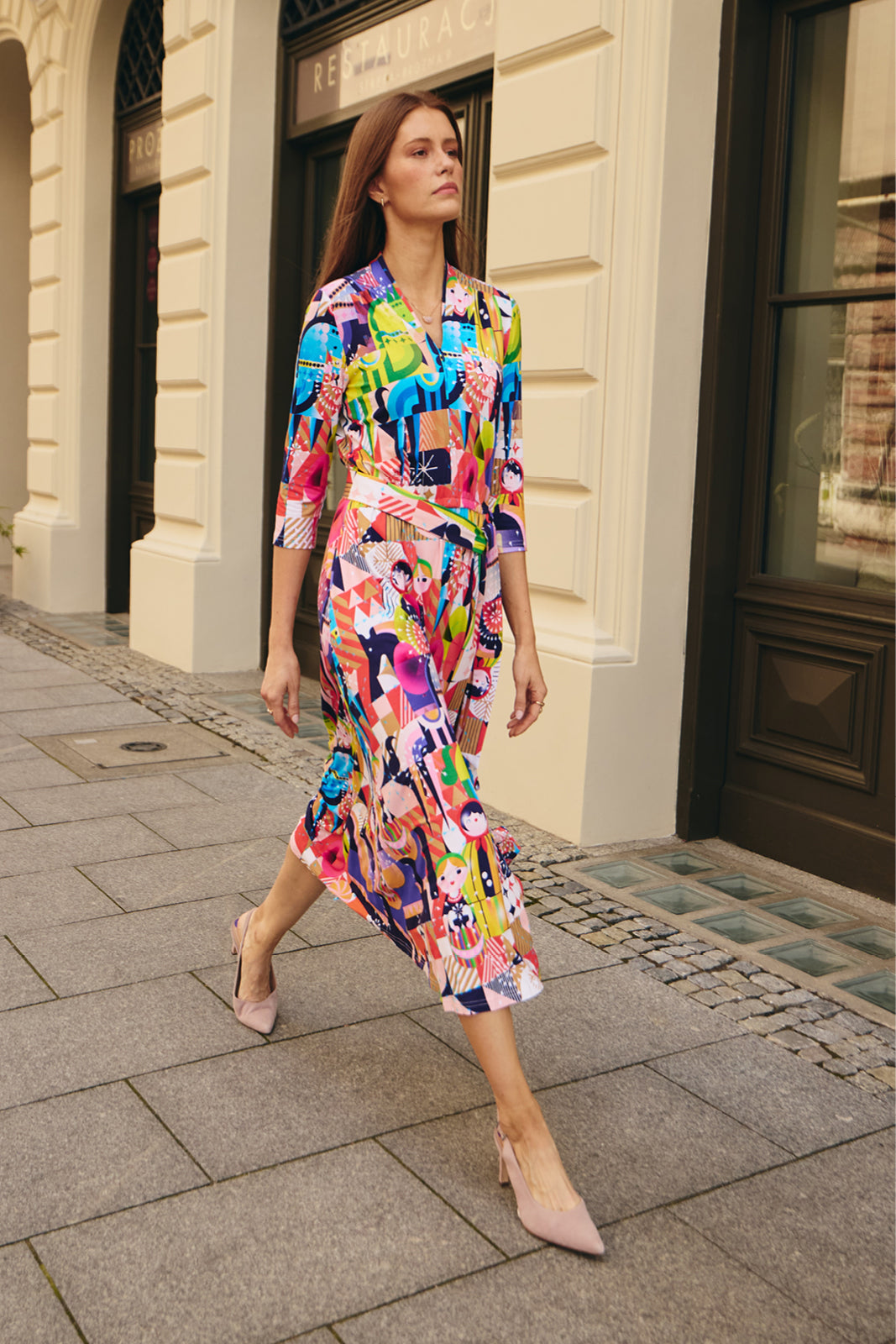 Kobieta w kolorowej, graficznej sukience midi z wiązaniem, idealna na codzienne stylizacje i self-care fashion